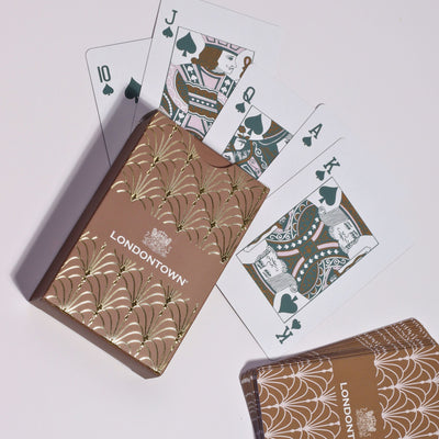 A deck of Parlour Party Playing Cards by LONDONTOWN, housed in a luxurious gold decorative box, best enjoyed in great company, featuring the 10, Jack, Queen, and King of spades.