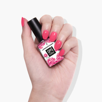 A hand with flamboyant pink manicured nails holds a bottle of LONDONTOWN Electric Flamingo nail polish.