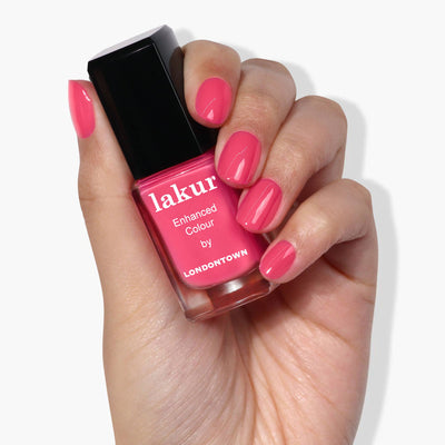 A hand flaunts a bottle of pink nail polish labeled "Electric Flamingo by LONDONTOWN" with matching flamboyant pink nails.