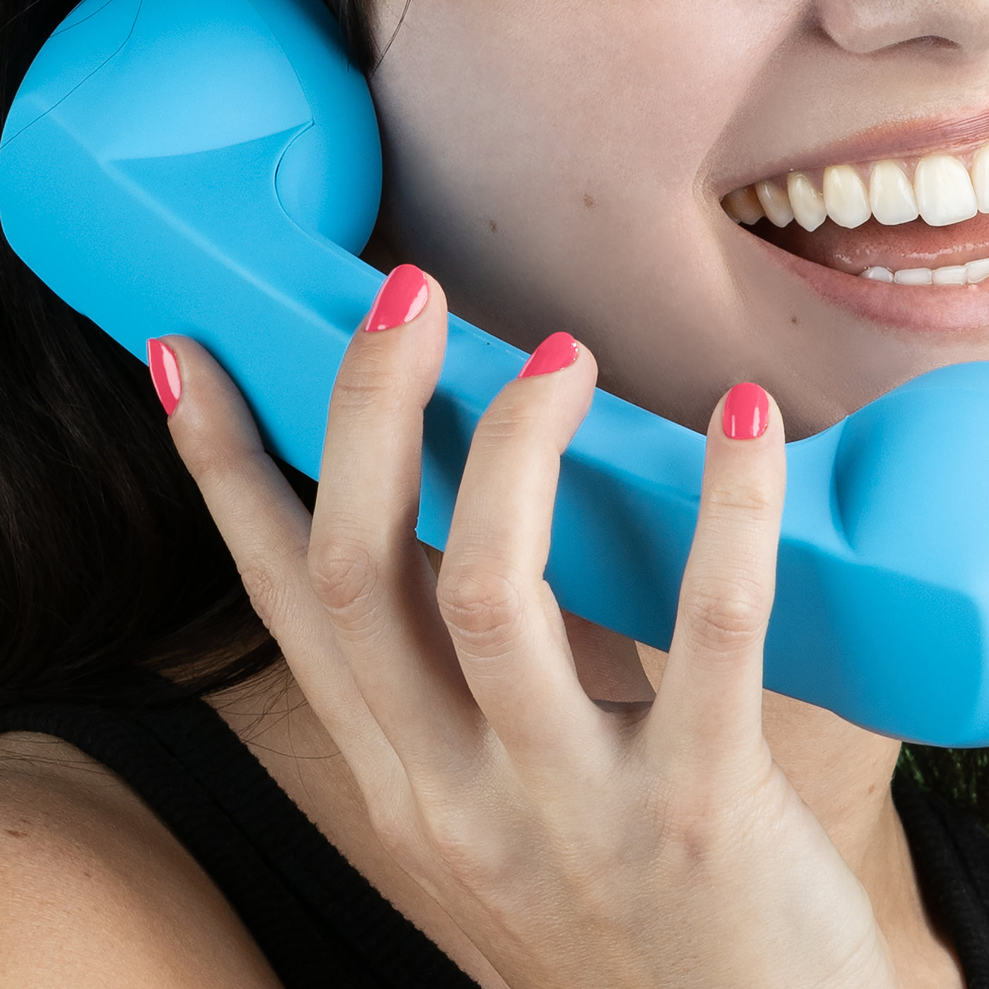 Person holding an Electric Flamingo handset by LONDONTOWN with pink painted nails, smiling, and showing white teeth.