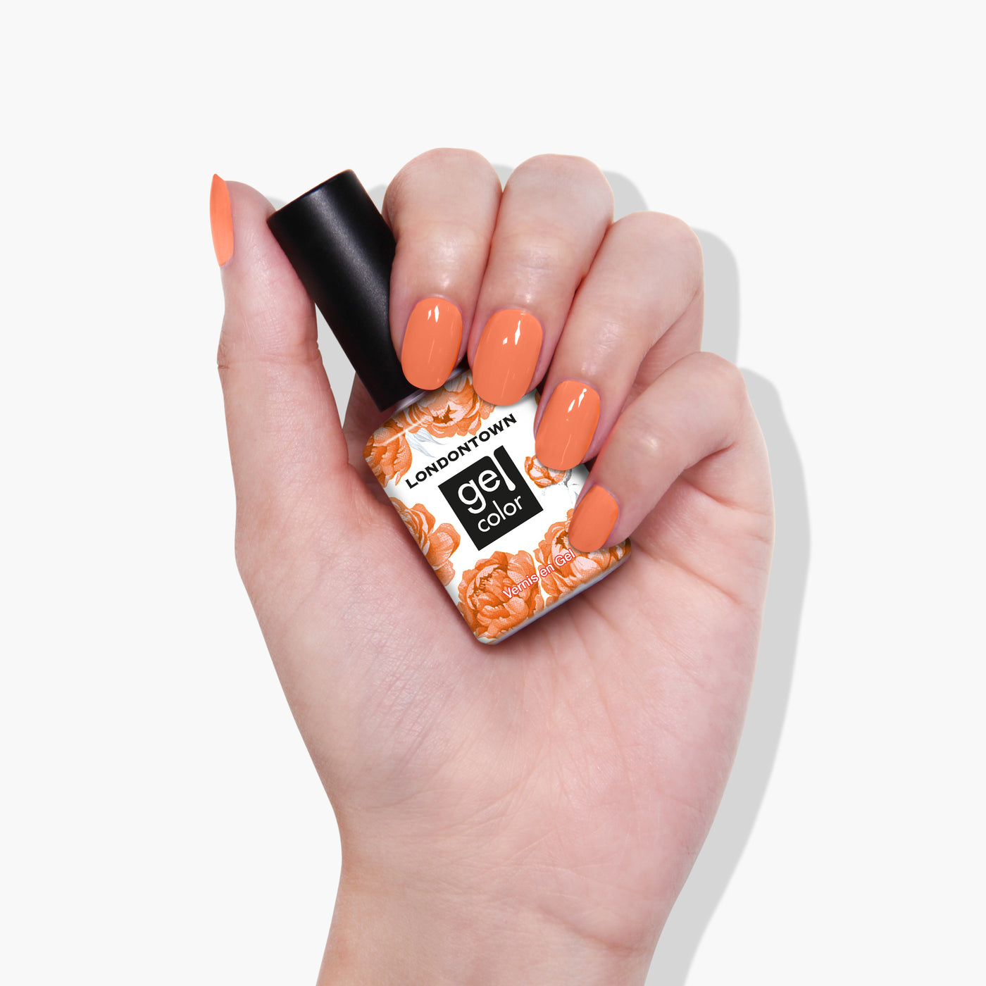 A hand with manicured nails is holding a bottle of LONDONTOWN Gel Color nail polish in the vibrant Paloma shade with a floral-patterned label, reminiscent of California peach.