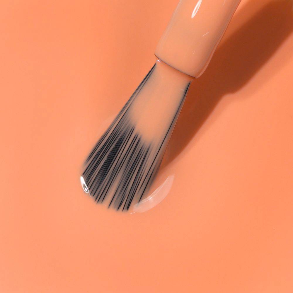 Close-up of a paintbrush with black bristles dipped in wet, vibrant Paloma California peach-colored paint by LONDONTOWN.