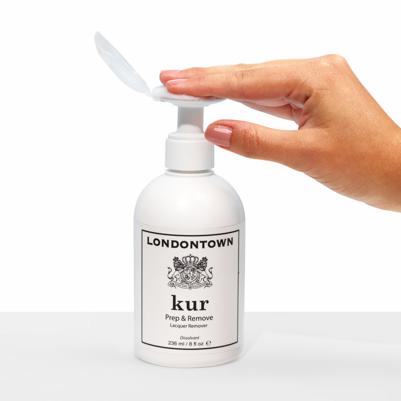 A hand presses a white pump bottle labeled "LONDONTOWN Prep & Remove Acetone Lacquer Remover," a gentle acetone lacquer remover ideal for nail polish and gel removal.