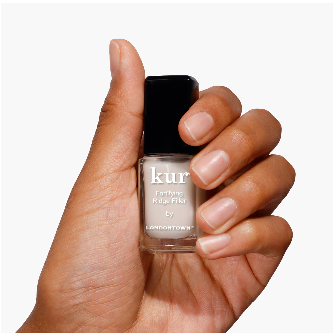 A hand holds a small bottle of Fortifying Ridge Filler by LONDONTOWN, showcasing a black cap and beige label. This essential base coat effortlessly smooths ridges for a flawless manicure.