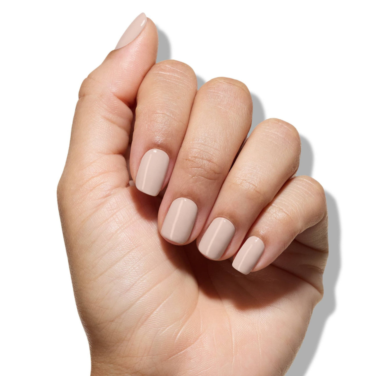 A hand with neatly manicured nails, perfected using LONDONTOWN's Fortifying Ridge Filler to conceal ridges, is painted in a neutral beige color against a white background.