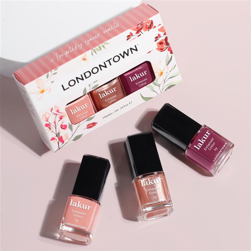 Three bottles of LONDONTOWN's Berry Blossoms lakur nail polish, in various shades, are showcased with floral packaging, ideal for an elegant occasion. Embrace the blooming palette and elevate your style effortlessly.