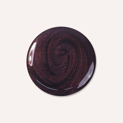 The Spilled Wine by LONDONTOWN is a circular, dark purple object with a glossy, swirled texture and subtle sparkles, reminiscent of pinot noir under candlelight.