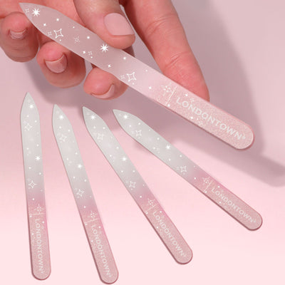 A hand holds a Glass Nail File - Pink Sparkle by LONDONTOWN, showcasing its effortless and damage-free nail filing. Below, four identical files are neatly arranged, each proudly featuring "LONDONTOWN.