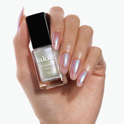 Close-up of a hand holding a bottle of Starry Chrome nail polish by LONDONTOWN. The nails are polished with a shimmery, crème-to-chrome color.