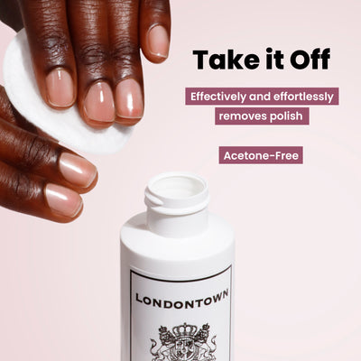 Hand using a cotton pad with LONDONTOWN's acetone-free nail polish remover from the Most-Loved & Must-Haves Set on a pink background—a must-have in your nail care routine for the holiday season.