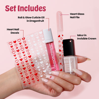 A hand holds the limited-edition Love & lakur Valentine’s Day Set by LONDONTOWN, featuring heart nail decals, cuticle oil, a nail file, and nail polish. Each exclusive item is labeled with its description.