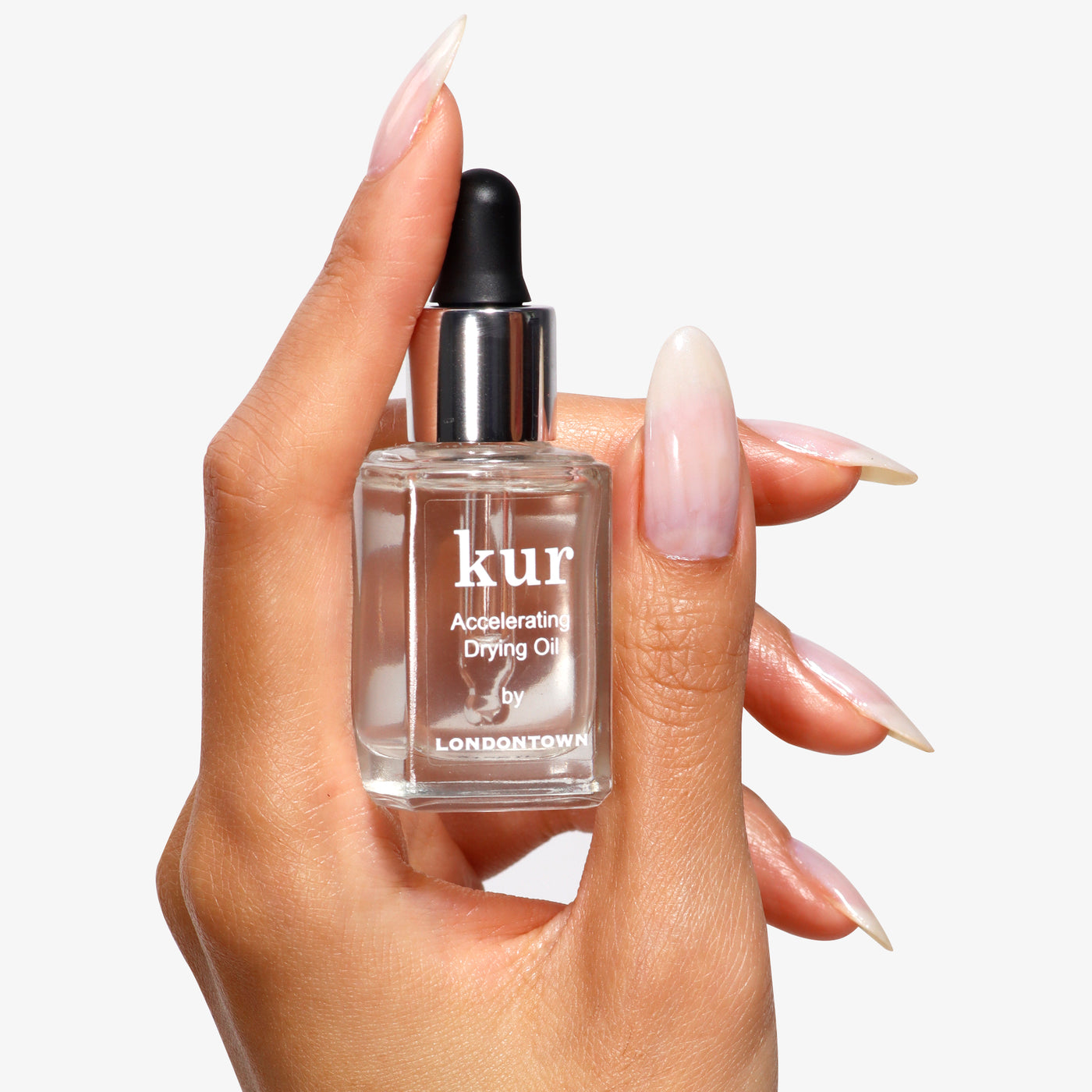 A hand holds a bottle of Accelerating Drying Oil by LONDONTOWN, showcasing its botanical oil blend for quick-drying manicures.