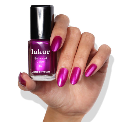 A hand with shimmering magenta nail polish holds a matching bottle of Alexa, Let's Dance! by LONDONTOWN against a white background.