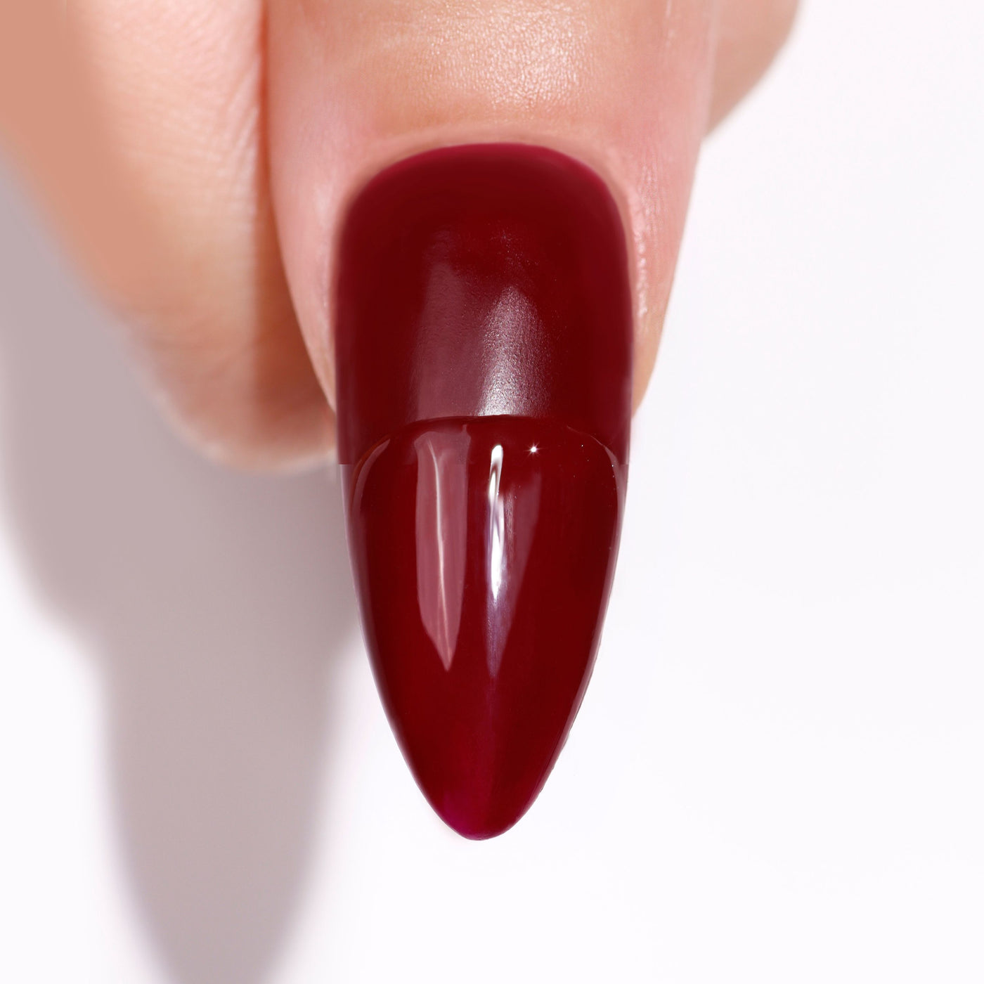 A hand flaunts a glossy dark red fingernail, enhanced by LONDONTOWN's High Gloss Top Coat, gleaming brilliantly against a white backdrop.