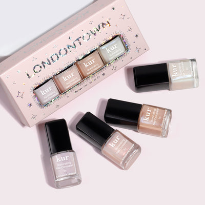 Four mini bottles from the Illuminating Essentials Mini Concealer Set by LONDONTOWN are displayed next to their packaging, offering an exclusive touch for an Extra Ordinary finish.