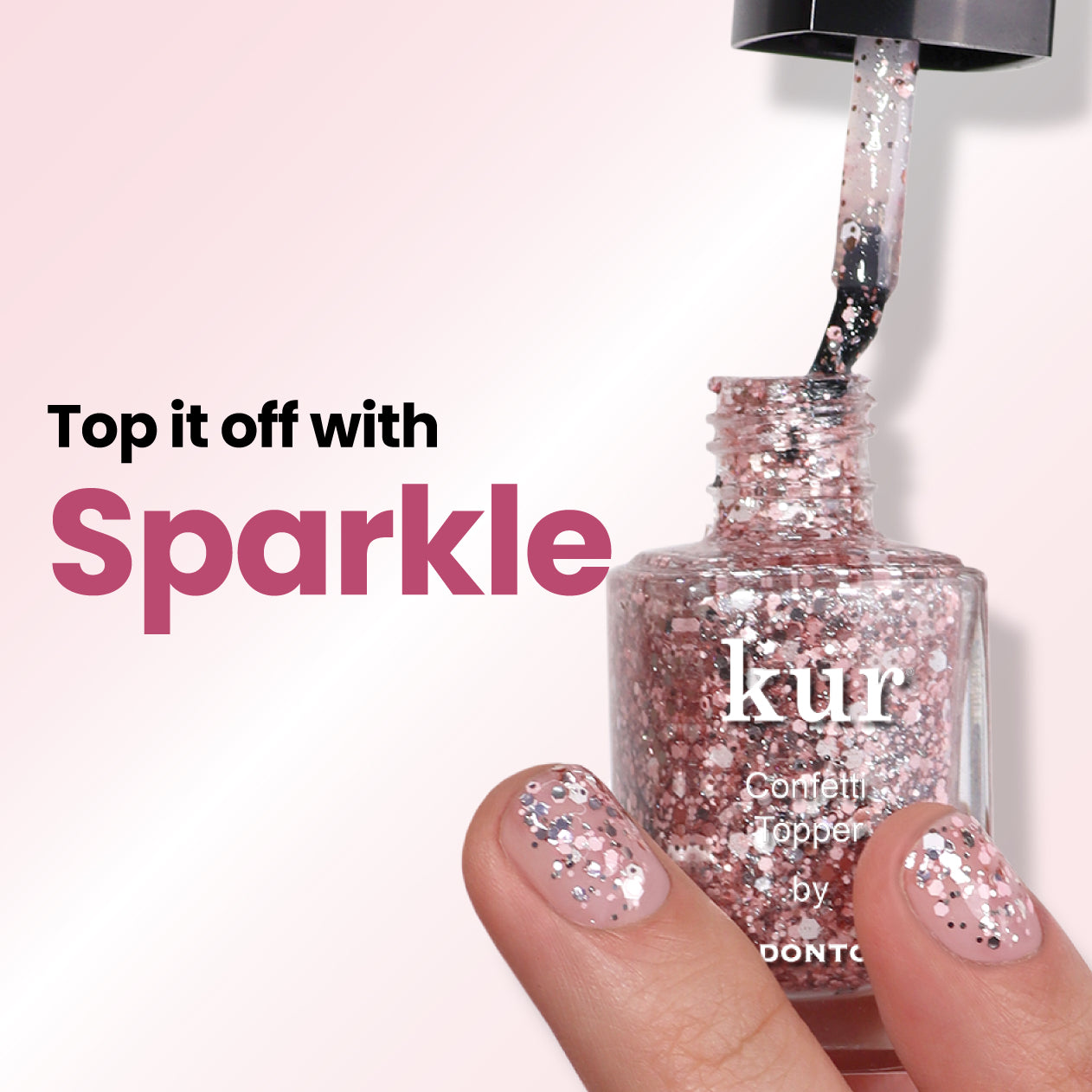 Open a bottle of LONDONTOWN's Snowglobe Confetti Topper nail polish, featuring a brush applicator and pink glitter. Text: "Top it off with the perfect sparkle finish." Close-up of fingers with polished nails.