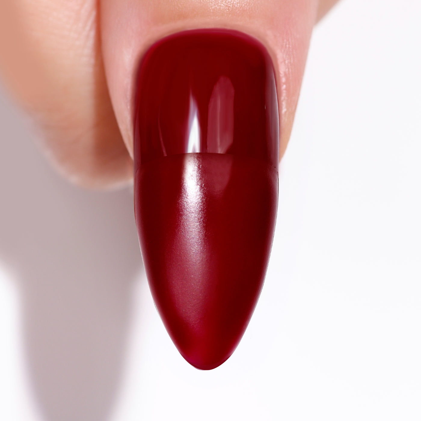 Close-up of a fingertip with a matte, dark red almond-shaped nail, using LONDONTOWN's Matte Top Coat (Professional), exuding an ultra-luxe vibe.