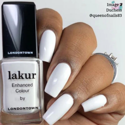 A hand with long, white, manicured nails holds a bottle of LONDONTOWN Lakur nail polish in "Duchess," perfect for achieving a chic French manicure.