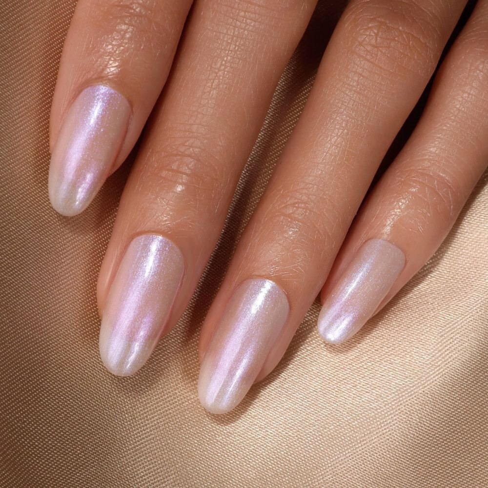 A close-up of a hand showcases the Pixi Chrome Duo by LONDONTOWN, featuring glossy, crème-to-chrome iridescent pink nails on a beige surface, instantly elevating this stylish look.