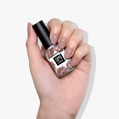 A hand confidently holds a LONDONTOWN gel polish bottle labeled 'Do Not Disturb,' featuring a floral design and showcasing nails painted in a bold mauve shade.