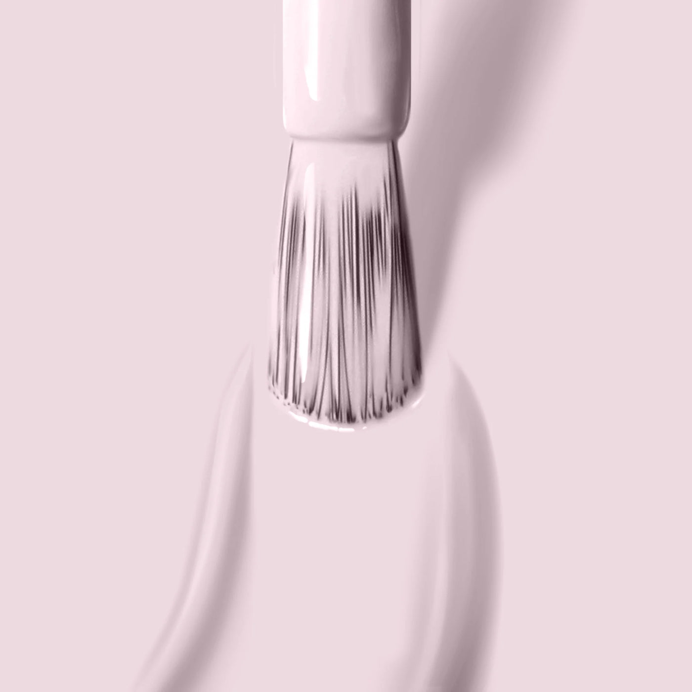 Close-up of a brush applying LONDONTOWN's "Afternoon Tea (Professional)" soft light pink crème nail polish on a matching pink background, creating a warm and cozy vibe akin to enjoying a cup of tea.