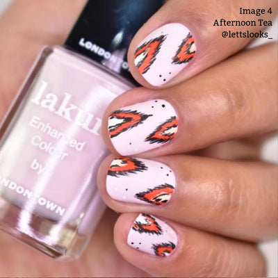 Close-up of a hand holding a bottle of LONDONTOWN's Afternoon Tea (Professional) nail polish. The nails are painted white with orange and black flame-like designs, perfect for a warm and cozy vibe. Text on the image reads: "Image 4 Afternoon Tea @lettslooks_.