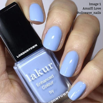 Close-up of a hand holding a bottle of LONDONTOWN's Amalfi Love (Professional) nail polish, enriched with Florium Complex. The nails are painted in the same light blue color, radiating beach vibes. Text on the image reads, "Image 1 Amalfi Love @oliveave_nails.