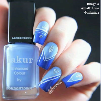 Close-up of a hand with blue gradient nail polish featuring geometric white line designs, holding a bottle of LONDONTOWN's Amalfi Love (Professional) nail polish in a matching shade. Infused with Florium Complex, this vegan, cruelty-free formula brings beach vibes to your fingertips.