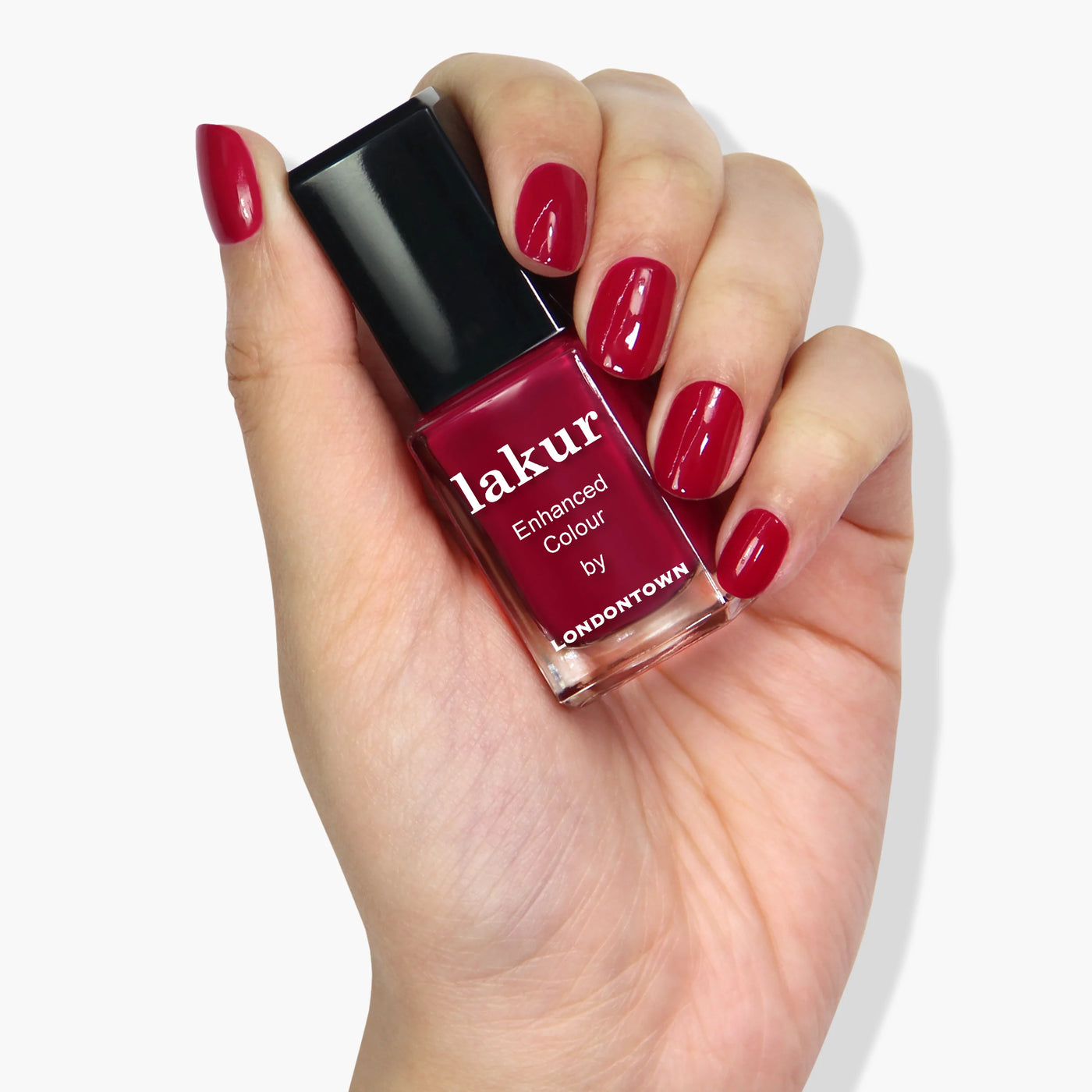 A hand holding a bottle of red nail polish labeled "Dragon Fruit (Professional) by LONDONTOWN," with nails painted in the same vibrant, cruelty-free red color.