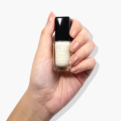 A hand with a nude manicure holds a bottle of "Fresh Glow Cuticle Remover (Professional)" by LONDONTOWN against a white background, offering an effective cuticle solution for dry and overgrown cuticles.