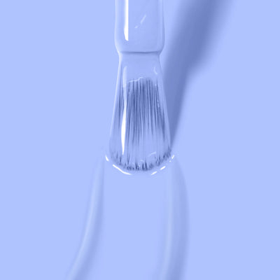 Close-up of a brush being coated with LONDONTOWN's In the Clouds (Professional) pale blue, cruelty-free nail polish against a light blue background.